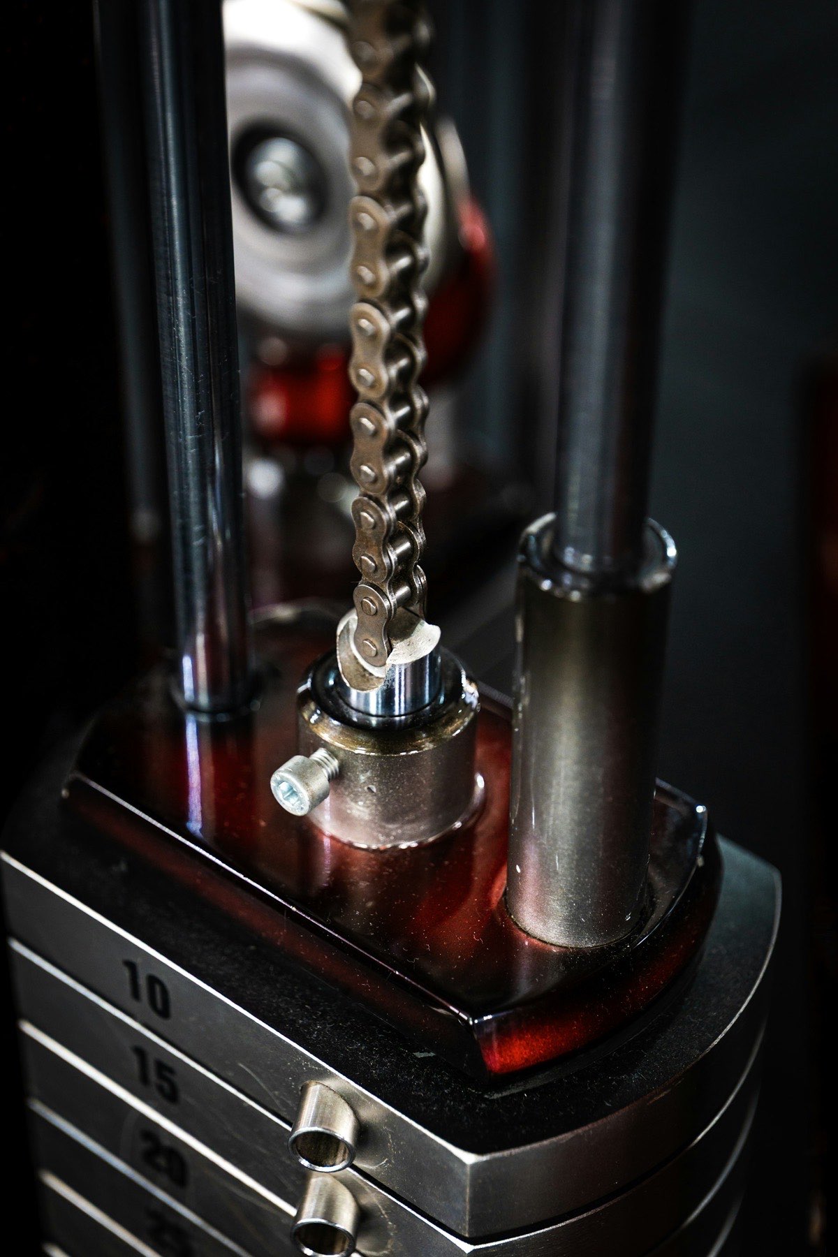 Close-up of a weight stack chain and guide rods on a selectorized gym machine